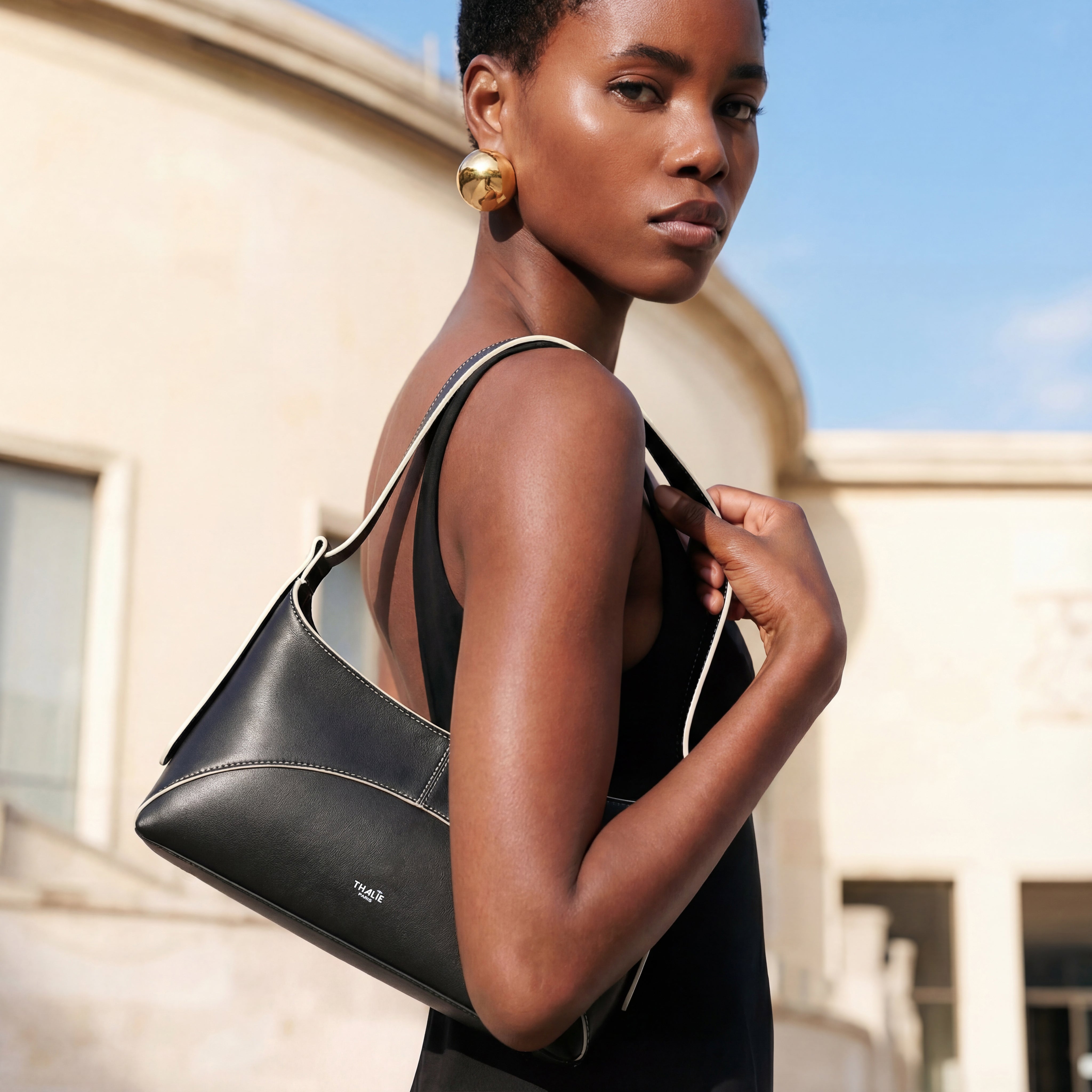 Ambre black vegan shoulder bag by Thalie Paris, crafted from plant-based leather, worn on the shoulder with a minimalist black outfit, highlighting refined lines and modern Parisian elegance.