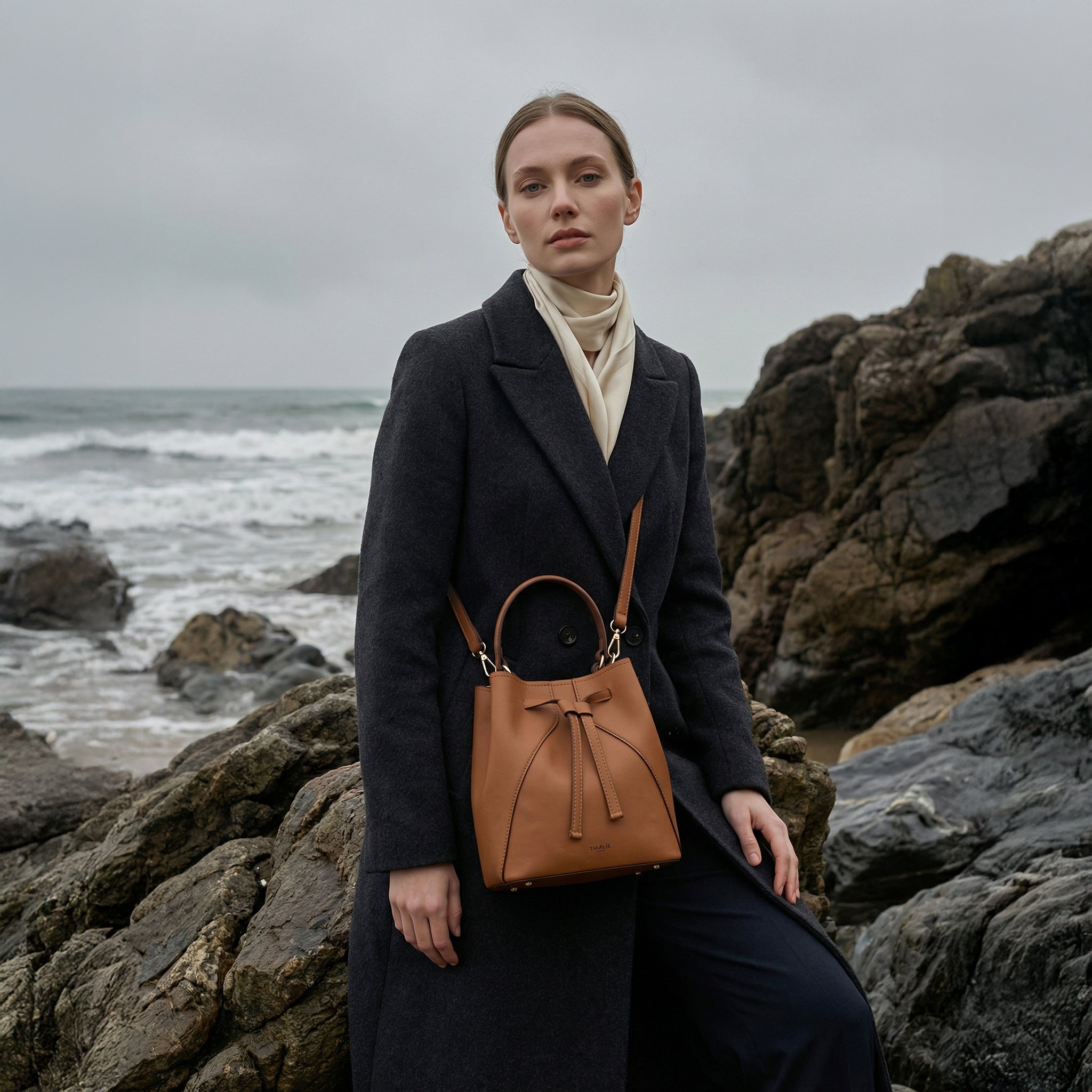 Model wearing the Mia vegan bucket bag in tan by Thalie Paris, crafted from plant-based cactus leather, featuring a top handle and crossbody strap